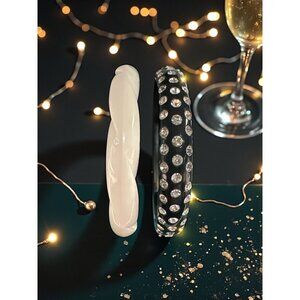 Elegant two‑bracelet set including a white twisted bangle and a black bangle ado